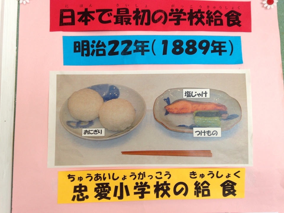Nanae <em>kyuushoku</em> in 1889, as replicated by the students at Ikusagawa Elementary. Two rice balls, fish, and a pickled vegetable. While school lunch in Nanae has diversified over the last 125 years to reflect Japan's increasingly globalized society, the core tenants remain.
